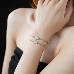 Detail of gold and silver Ruyi bracelets with green jade and zircon on model's wrist