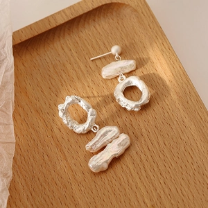 Baroque pearl earrings with lava texture silver metal hoops on a wooden tray