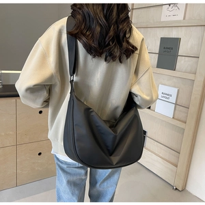 Modern black half-moon crossbody bag shown on model for daily style and size reference