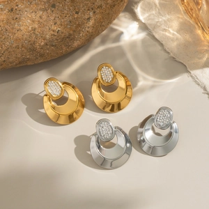 Close-up of geometric stainless steel earrings in gold and silver with crystal studs