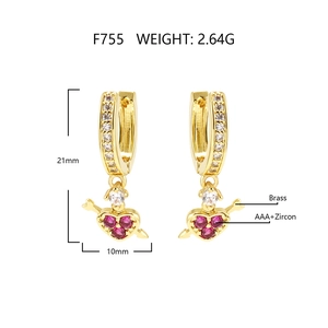 Macro view of heart-shaped gold-plated brass earrings with pink zircon stone details