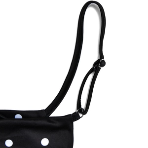 Detailed macro view of adjustable black straps and metal buckles on a polka dot dress