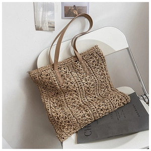Detail of hand-woven hollow flower pattern on straw tote bag with leather handles