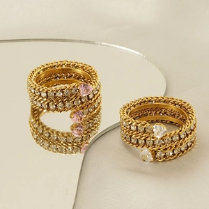 Macro detail of intertwined gold rings with pink and white heart crystals and pavé diamonds