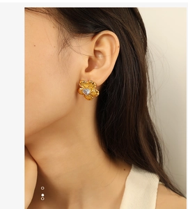 Detailed view of vintage gold flower stud earrings with central white zircon on a model
