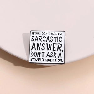 Macro d'un pin's carré en émail avec un texte sarcastique sur fond blanc épuré