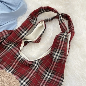 Detail of red plaid shoulder bag featuring soft brown sherpa trim and warm inner lining