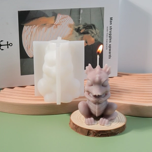 Detailed silicone mold and finished purple dinosaur candle on a green surface