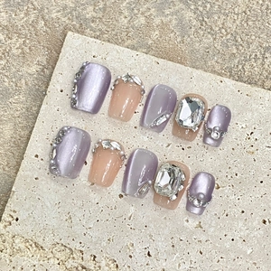 Handmade taro purple cat eye and nude pink press-on nails with sparkling rhinestones