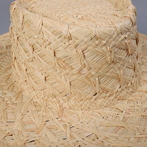 Close-up of handmade raffia straw boater hat with a natural woven texture in tan