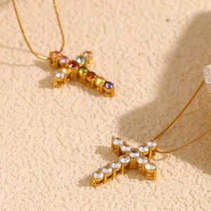 Detail of 18K gold-plated cross pendants with colorful crystals and white gemstones