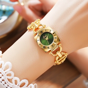 Close-up of a vintage gold alloy bracelet watch with a green dial on a woman wrist
