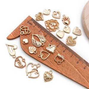 Golden DIY charms for jewelry making shown with a ruler for size reference on white background