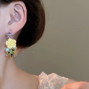 Detail of flower earrings with purple rhinestone and yellow rose on model's ear