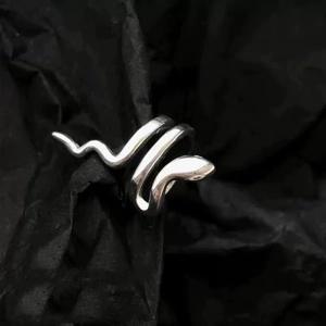 Macro shot of silver snake ear cuff with mirror-polished finish on dark textured background