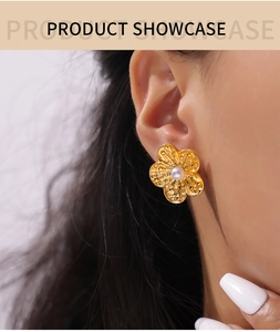 Detailed close-up of a gold floral earring with a white pearl center on a model