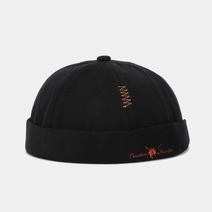 Detail of black docker hat with orange wavy embroidery and Freedom & New Life text print