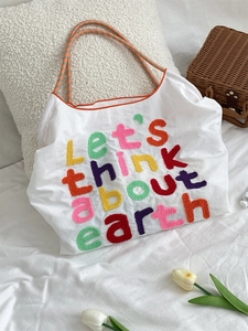 White canvas tote bag with colorful earth embroidery and orange checkered handles