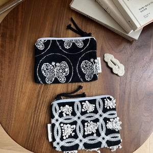 Detail of black canvas mini pouches with butterfly and floral embroidery and zipper