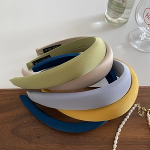 Chic padded wide headbands in matte candy colors stacked on a natural wooden table