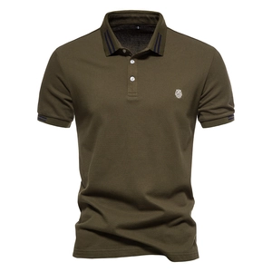 Détail d'un polo vert armée montrant la texture coton piqué et le logo lion brodé blanc