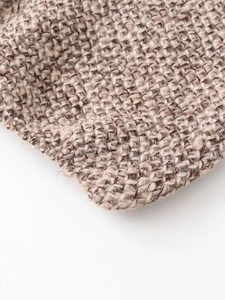 Close-up of brown and beige chunky knit fabric texture showing thick yarn fibers
