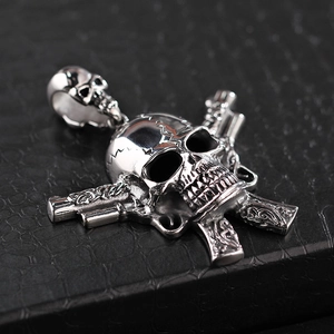 Detailed view of punk style stainless steel skull with crossed pistols pendant