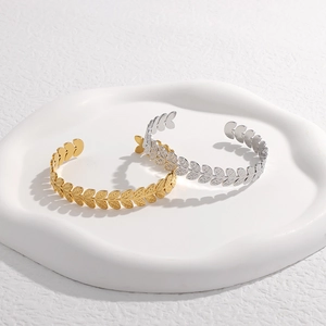 Detalle de brazaletes ajustables en forma de hoja de acero inoxidable en oro y plata
