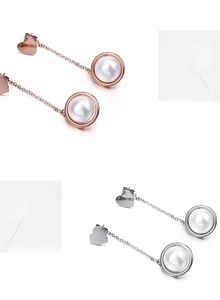 Detail of heart stud earrings with long chains and dangling pearls in rose gold and silver