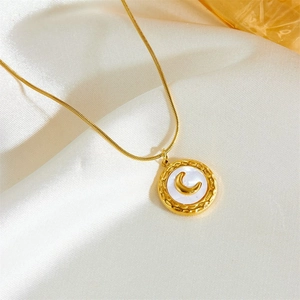 Detail of gold moon shell necklace pendant lying on soft premium silk background