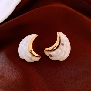 Close-up of 18K gold plated C-shaped earrings with marble texture on velvet background
