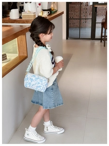Girl wearing light blue floral crossbody bag with wavy strap and sequins