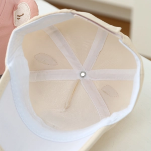 Detail view of the beige baby baseball cap showing internal six-panel stitching and lining