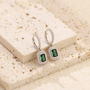 Detailed close-up of emerald green rectangle earrings with zircon halo on stone base