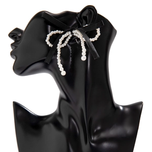 Detail of sweet ribbon bow earrings with faux pearls and elegant crystal tassels