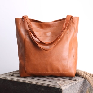 Vue détaillée du cabas vintage en cuir marron avec grande poche sur une caisse bois