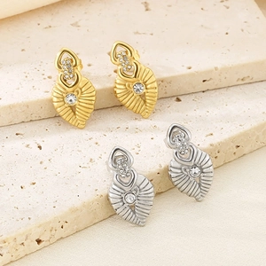 Detailed view of gold and silver leaf earrings with sparkling cubic zirconia on stone