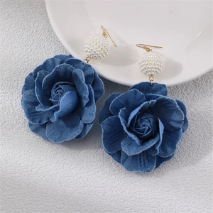 Macro view of blue denim camellia rose earrings with white pearl and gold metal hook