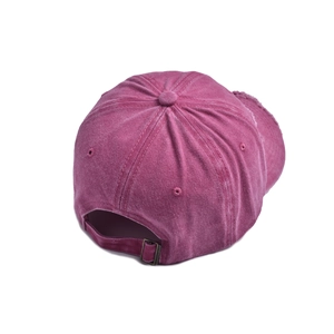 Detail view of the metal buckle and frayed edge on the pink washed cotton baseball cap