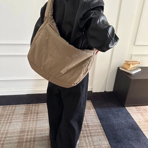Modern beige puffer tote bag styled on shoulder, showcasing its large soft structure and strap
