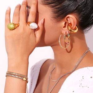 Close-up of gold stainless steel jewelry set featuring rings with green acrylic stones