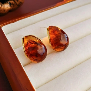Close-up of amber resin water drop earrings with gold metal plating in a jewelry box