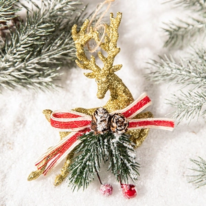 Golden Christmas reindeer ornament with pine cones and red bow on a snowy pine background