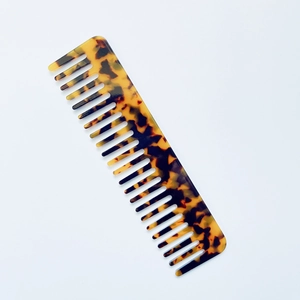Detail view of tortoiseshell wide-tooth hair comb with elegant acetate marble texture