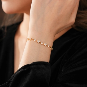 Sparkling star and round zircon gold bracelet shown on model wrist with elegant detail