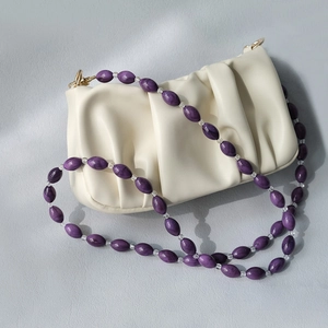 Close-up of white cloud bag with purple acrylic bead strap and wrinkled faux leather texture