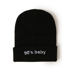 Détail d'un bonnet en tricot noir avec broderie 90's baby et texture côtelée douce