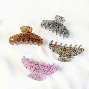 Set of large leopard print claw clips in four colors on a white fabric background