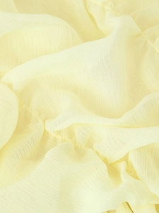 Macro shot of light yellow pleated chiffon fabric with fine vertical texture and soft finish