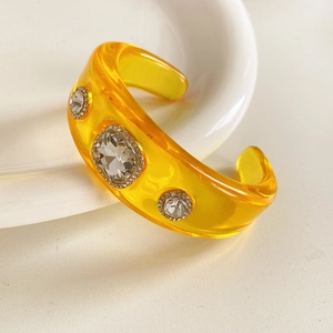 Detailed macro view of yellow resin bangle featuring three large rhinestone clusters